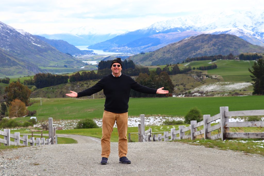 Hombre con brazos abiertos y detrás paisaje